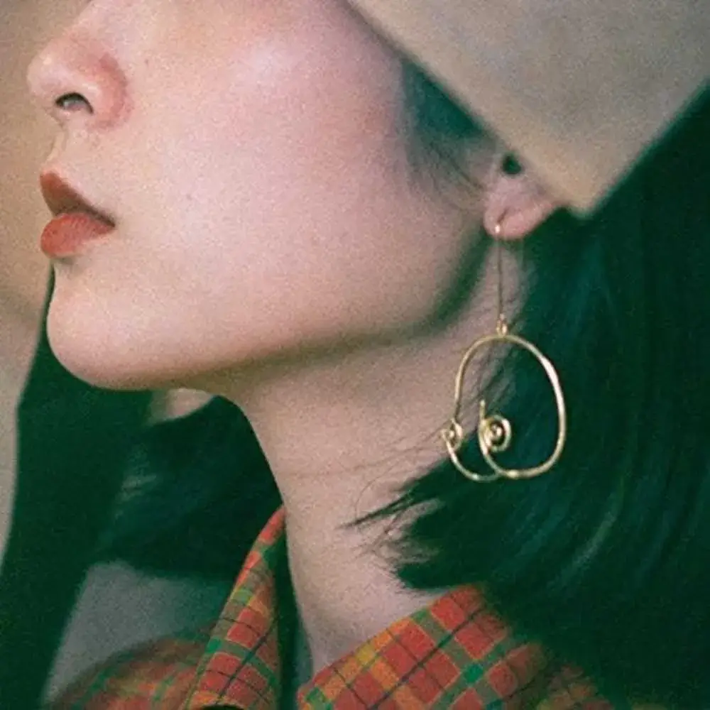 close-up of woman's ear with golden geometric boob earring