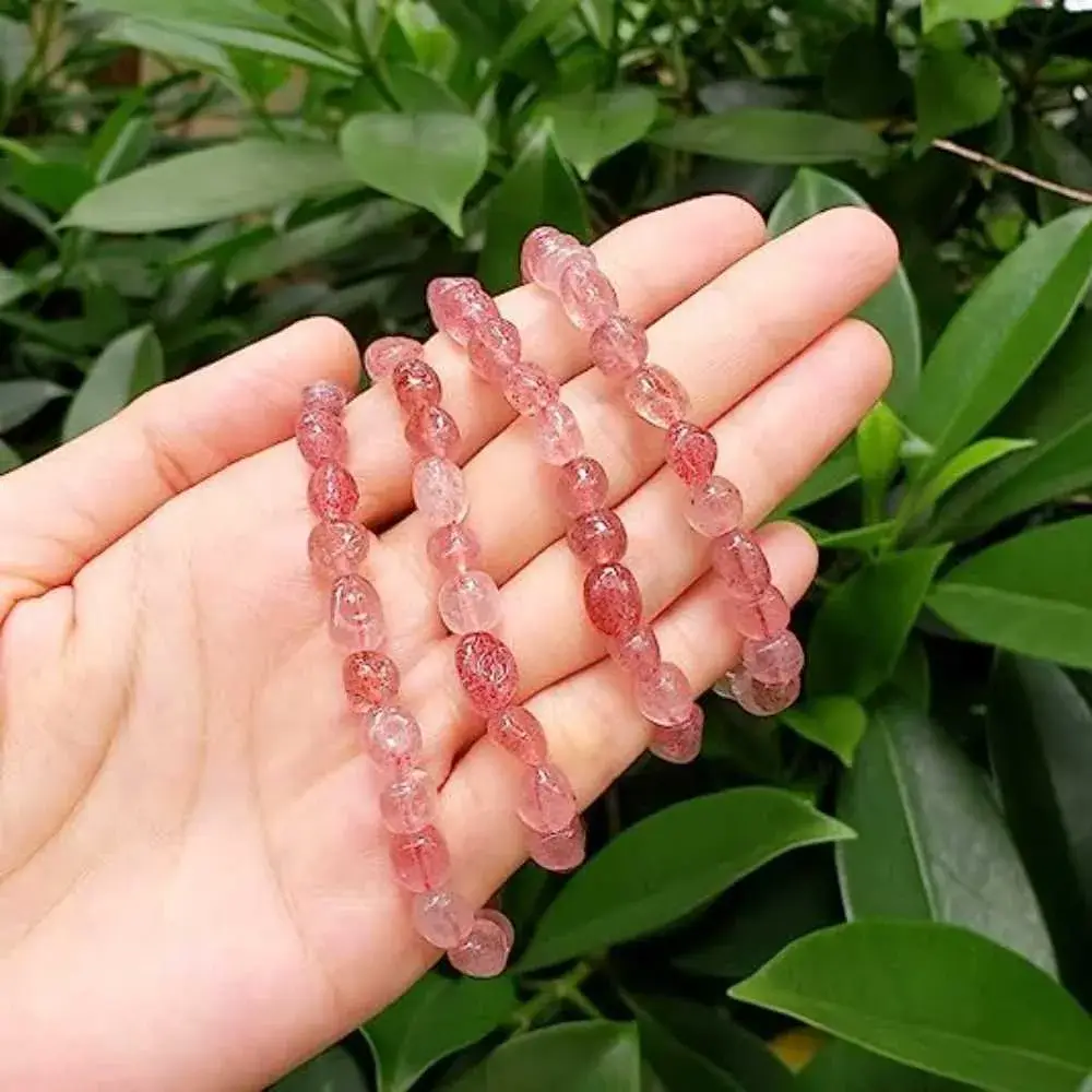 close-up of a palm with four strawberry quartz bracelets