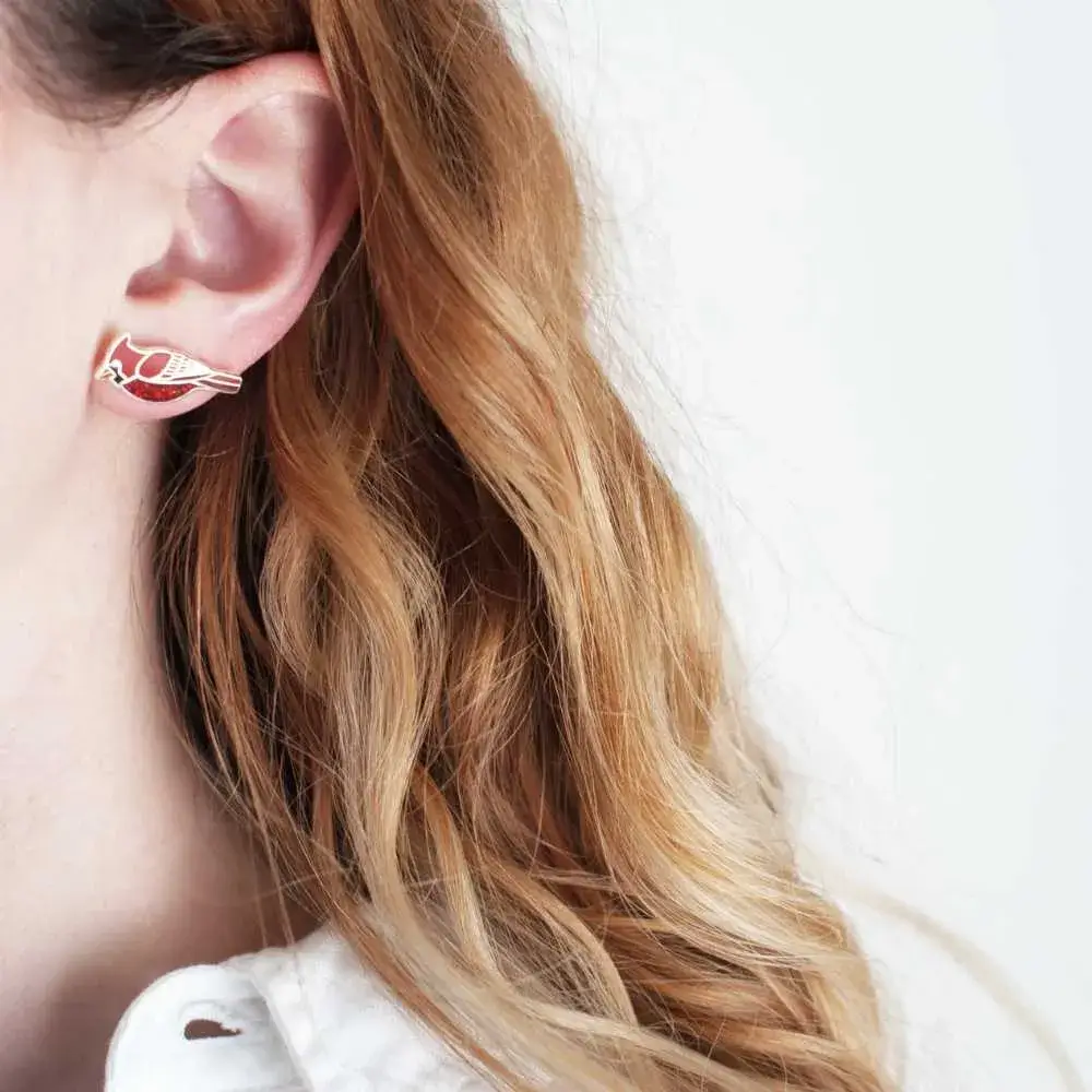 blonde girl's ear with a cardinal earring