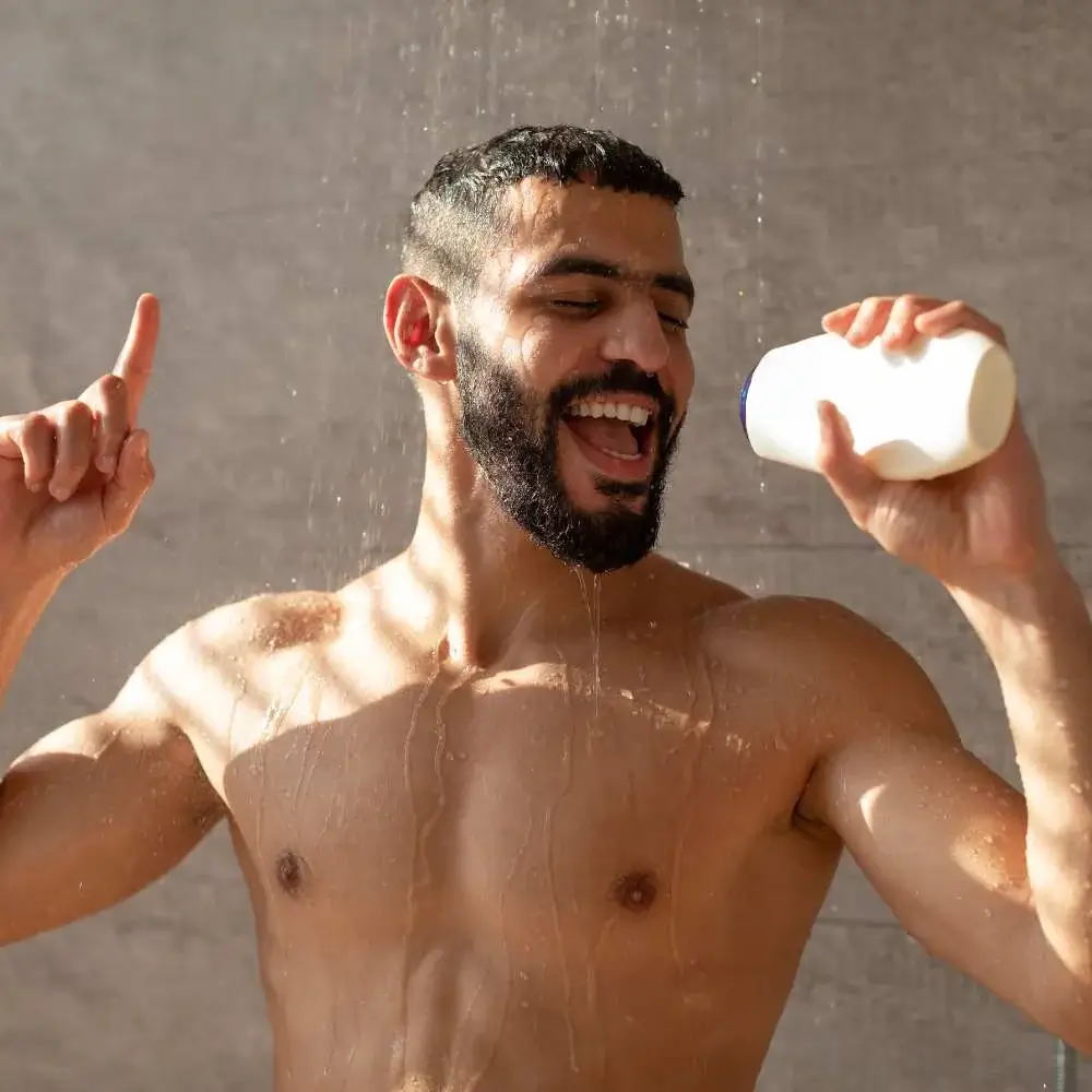 Man's hand holding a bottle of the best dandruff shampoo for men