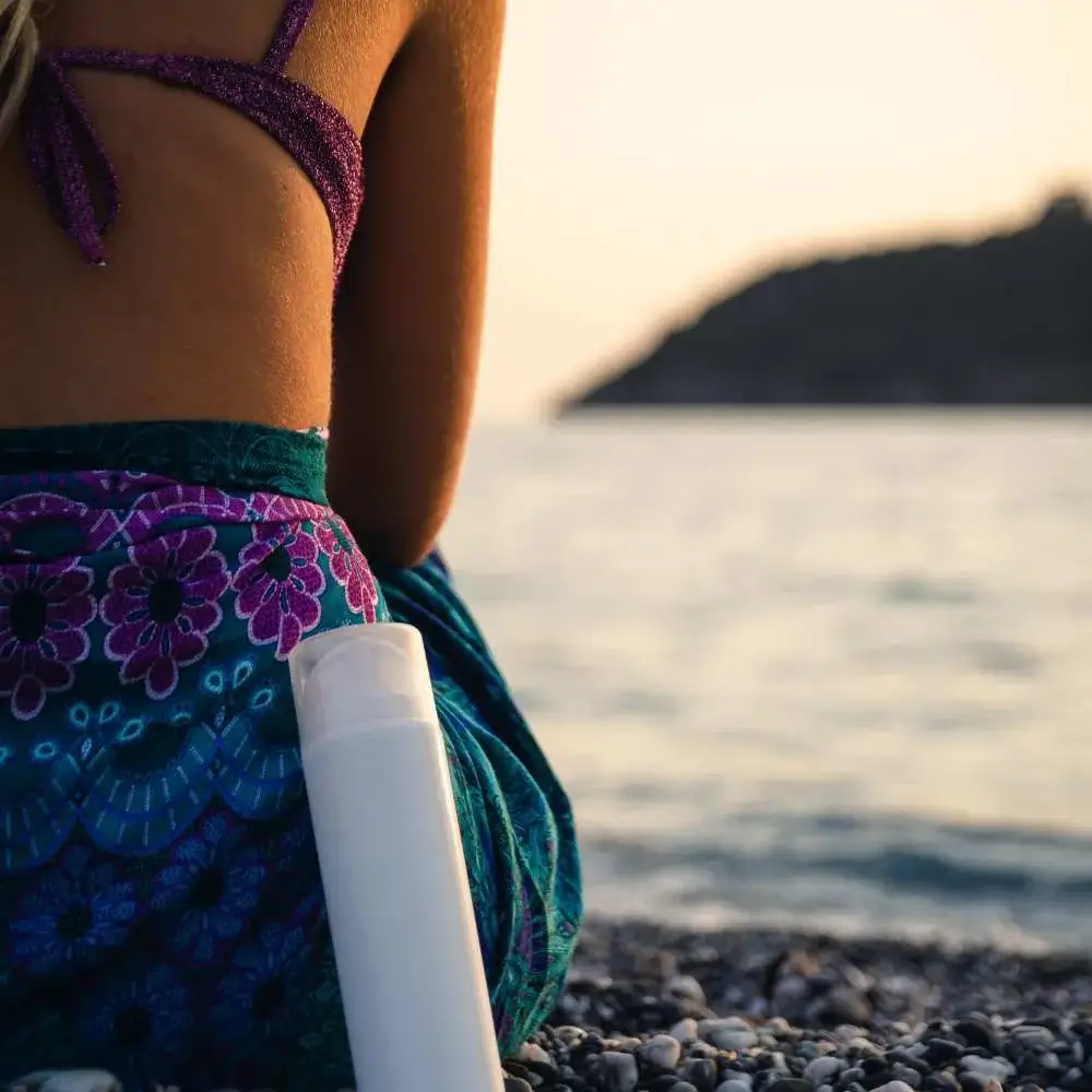 Tube of water-resistant sunscreen against a backdrop of beach scenery