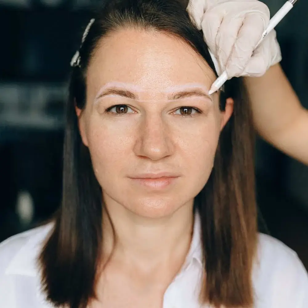 Artist in the process of microblading eyebrows to enhance their shape