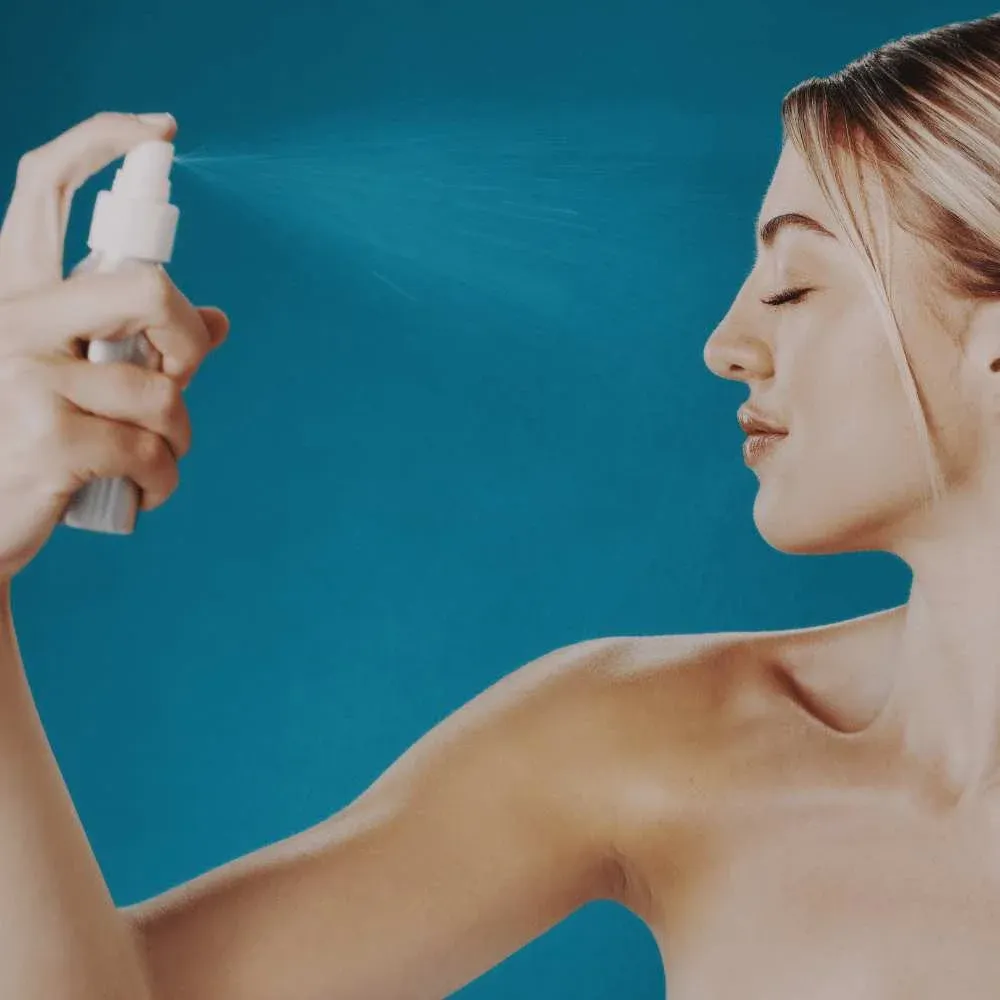Woman spritzing her face with the best setting spray for oily skin