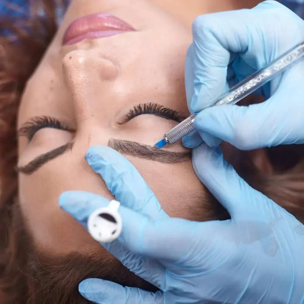 Professional artist performing microblading on a client's eyebrows