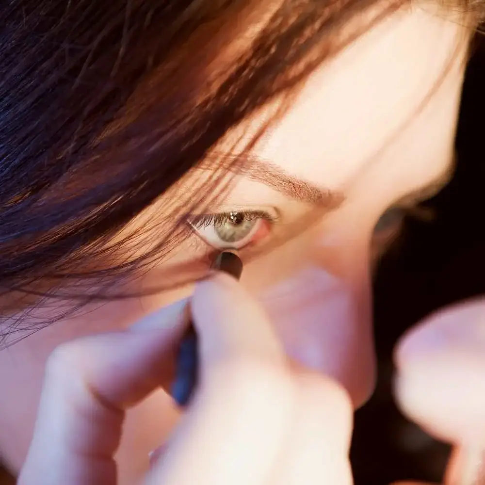 Woman expertly applying nude eyeliner to enhance her eyes
