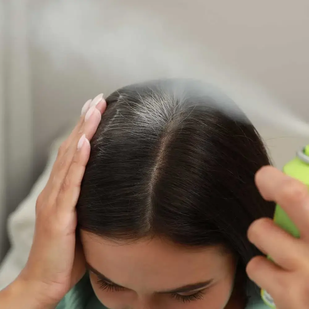 Woman applying the best dry shampoo to refresh her oily hair