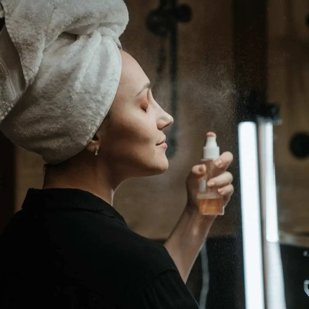 Woman spritzing setting spray to keep her makeup in place