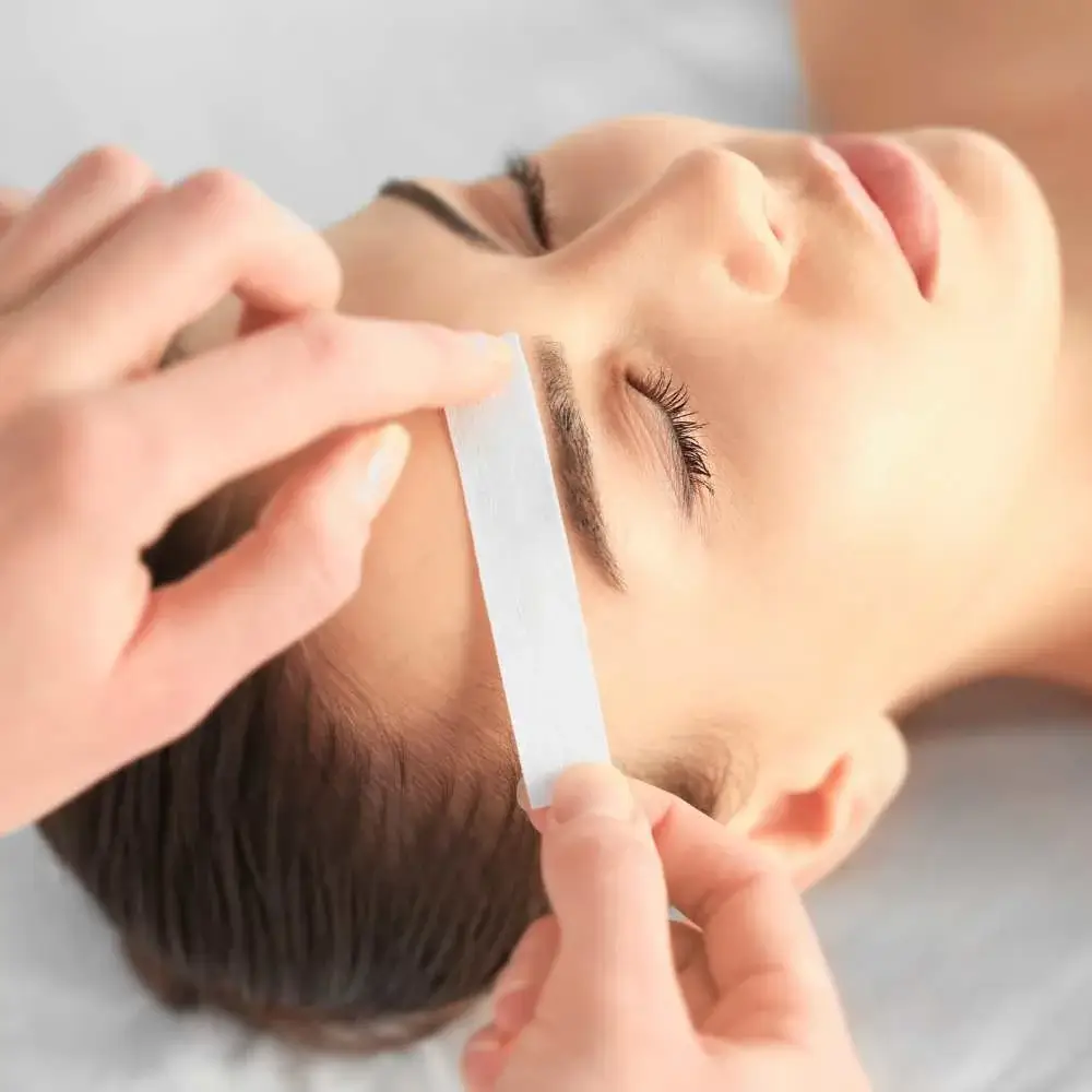 Woman expertly applying wax to shape her right eyebrow