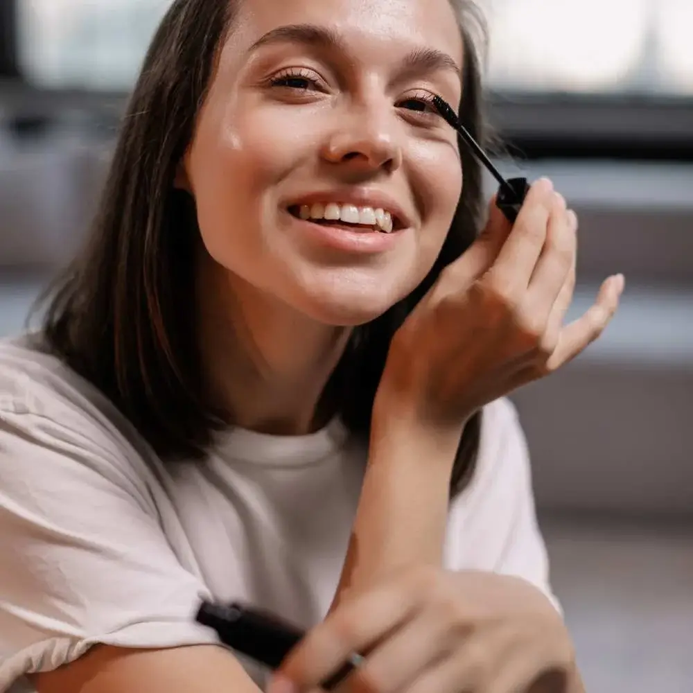 Professional makeup artist using brown mascara on a model's lashes