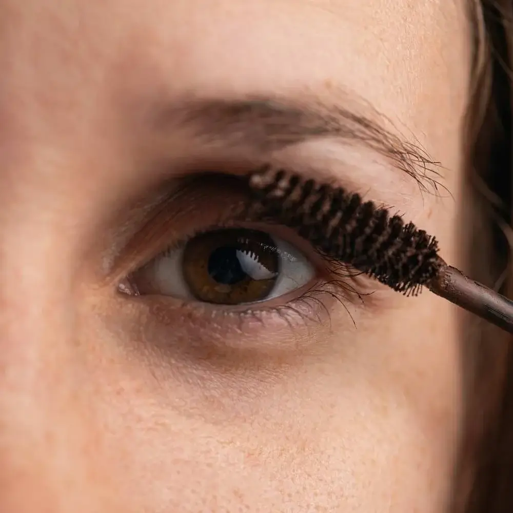Woman applying brown mascara for a softer, natural look