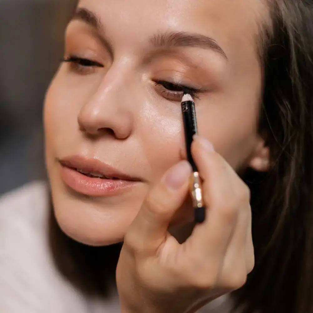 Woman applying nude eyeliner to her waterline for a bright-eyed look