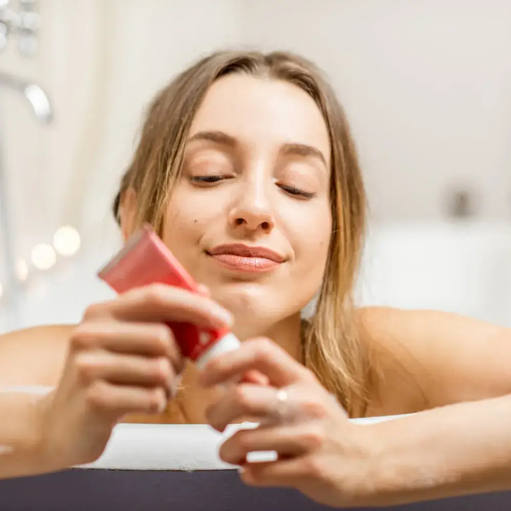 woman holding a red tube of face wash