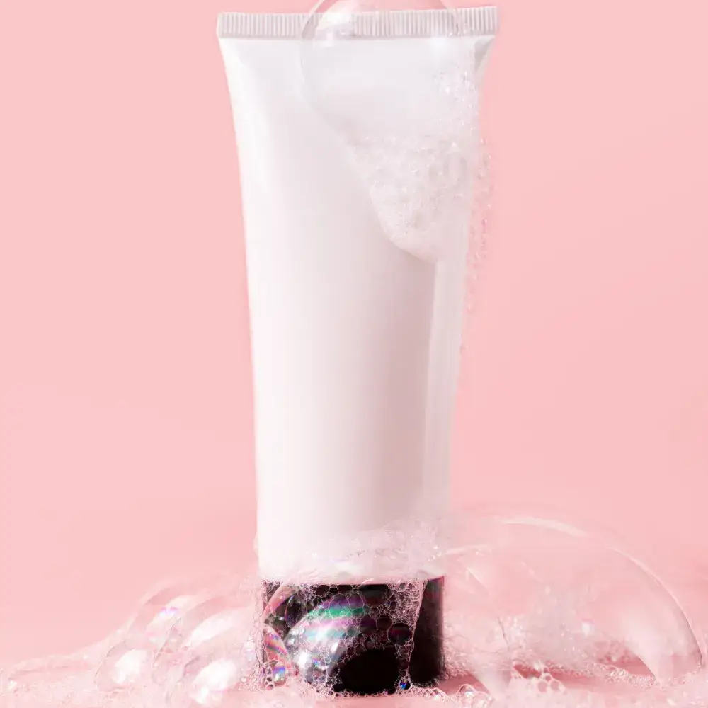 face wash tube with bubbles in a pink background