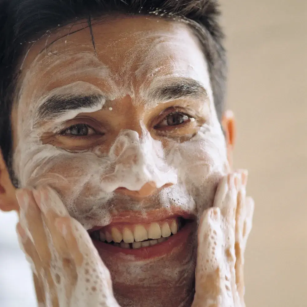 close up portrait of a man smiling while washing his face