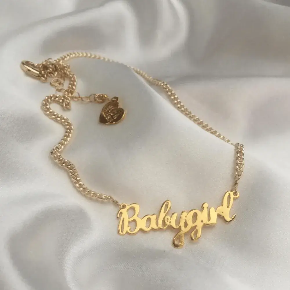 babygirl neklace gold on white fabric