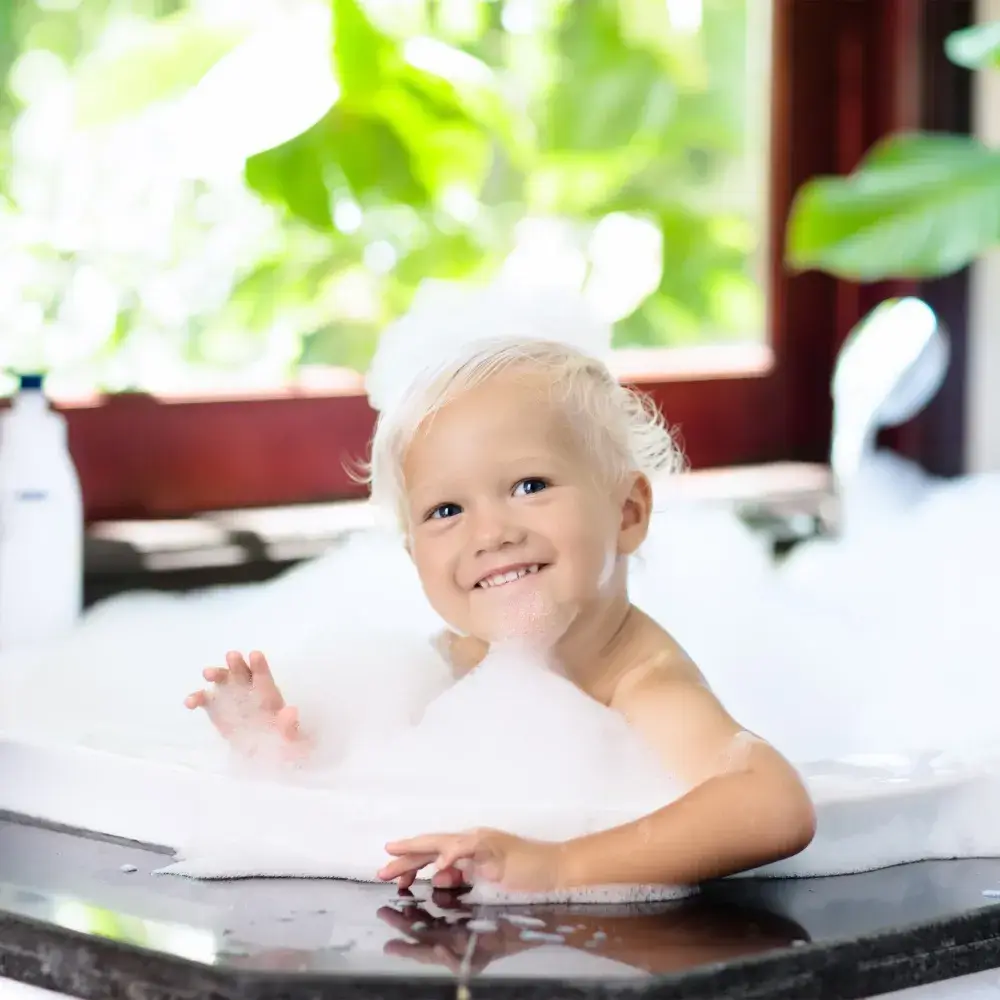 little boy smiling and enjoying his bubble bath
