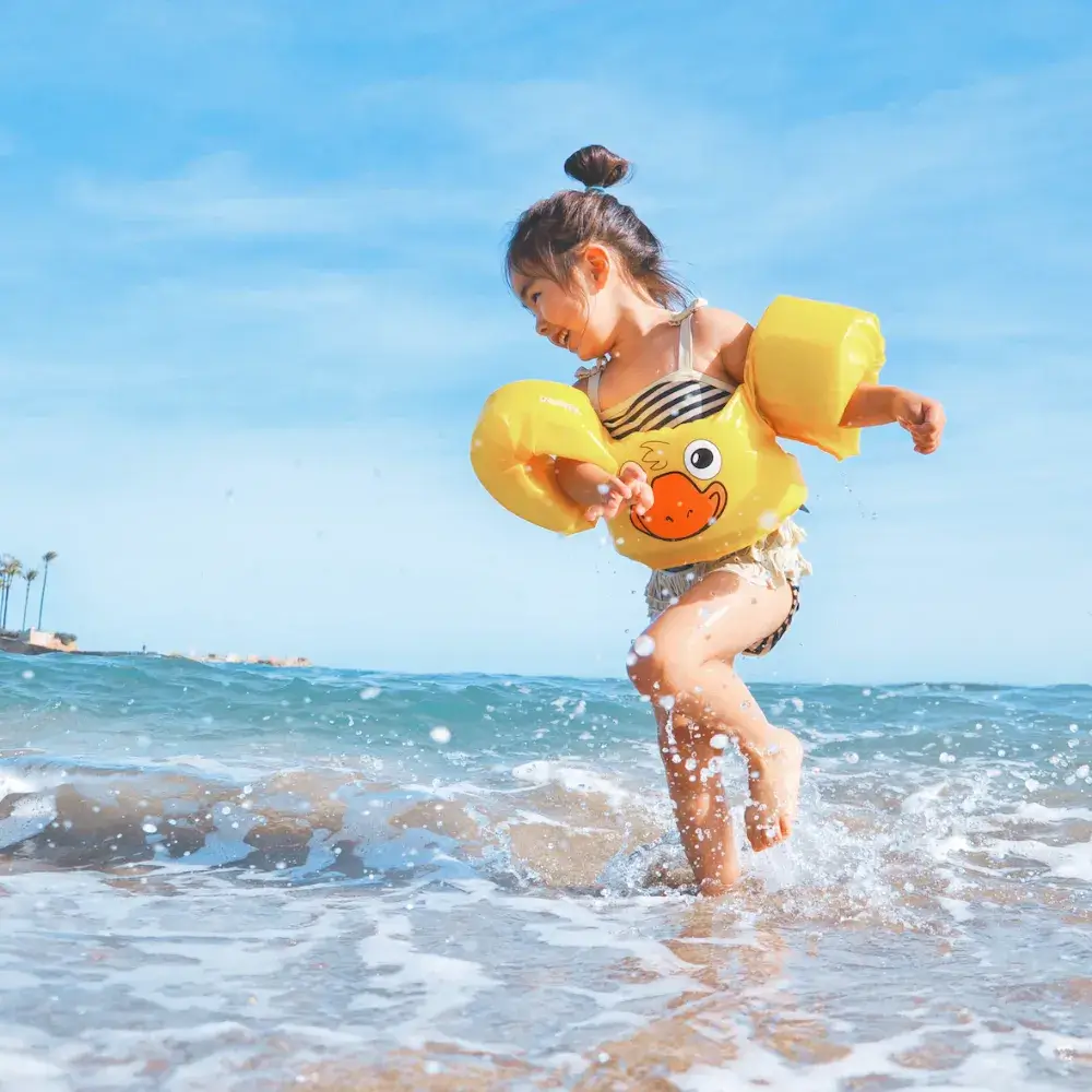 little girl happily enjoying the waves at the beach