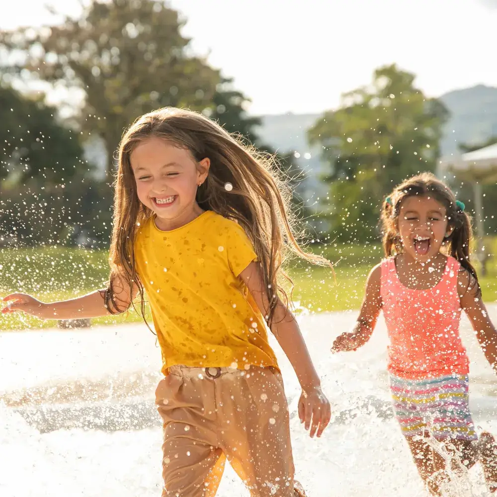 two girls happily running and making splash of water
