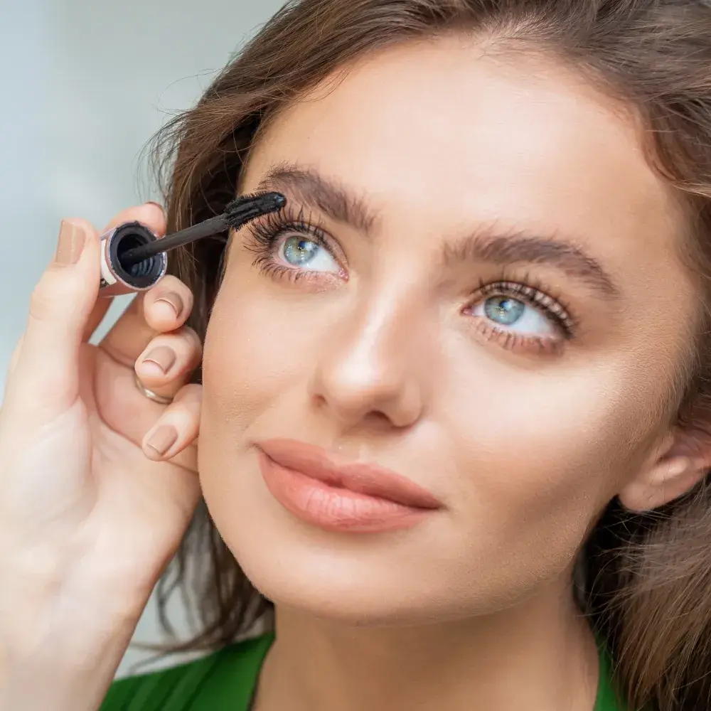 professional make up artist applying mascara to a beautiful young woman