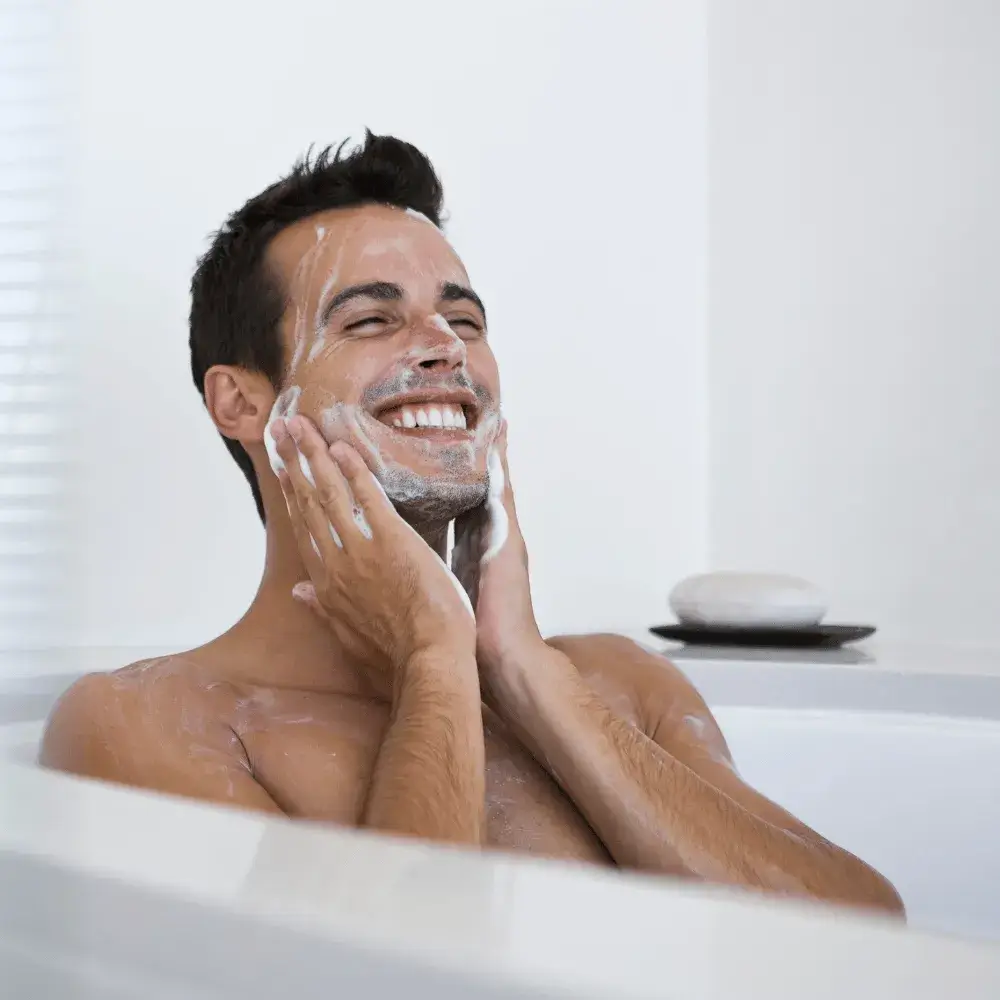 man smiling while washing his face
