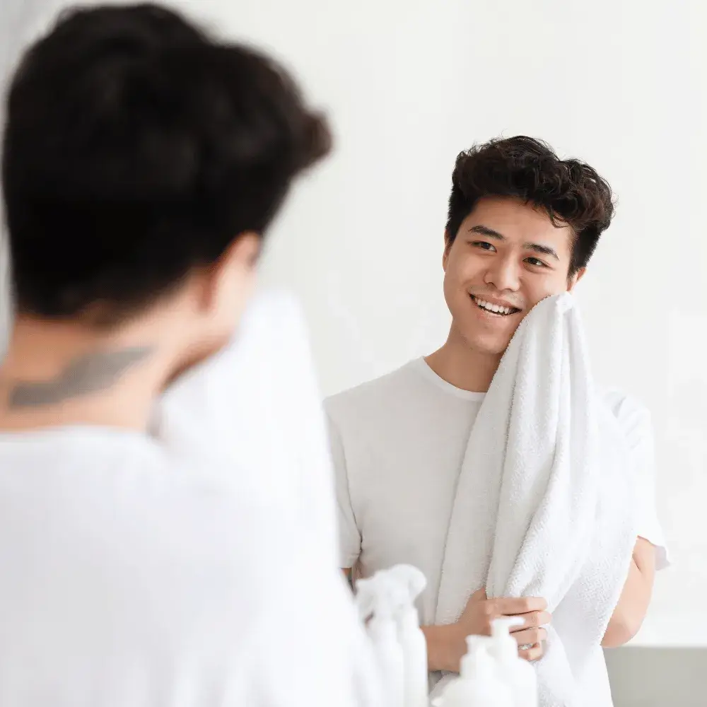 young man wiping his face with a white towel