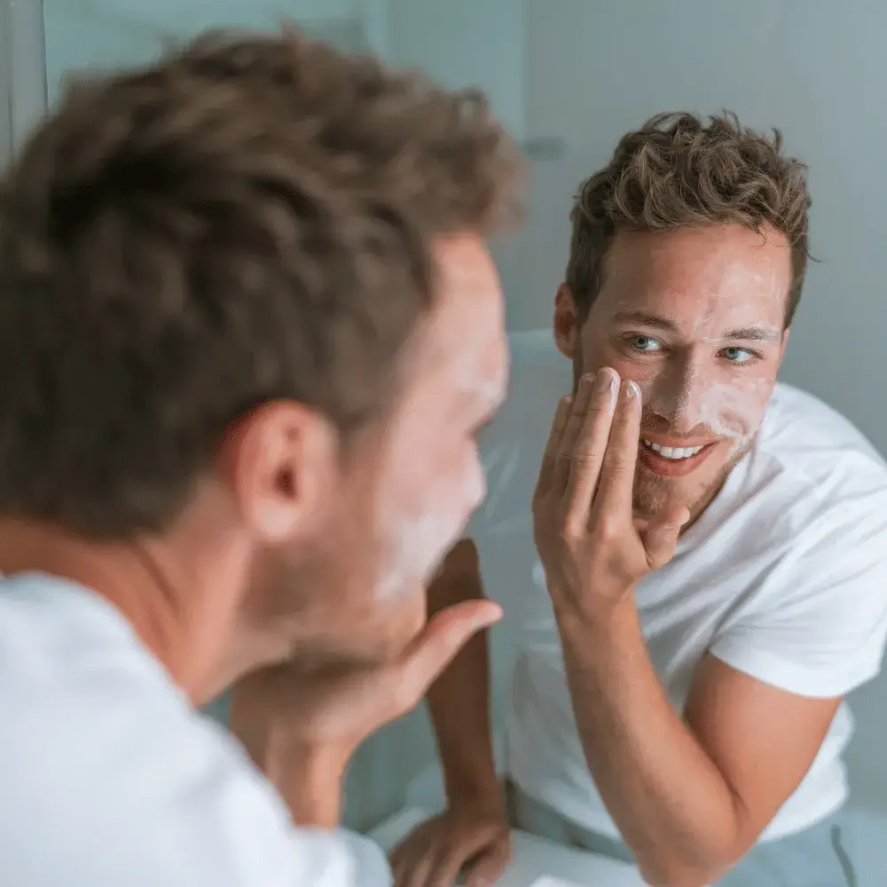 man washing his face in front of a mirror