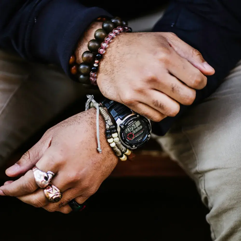 man's hands with bracelets, watch and rings