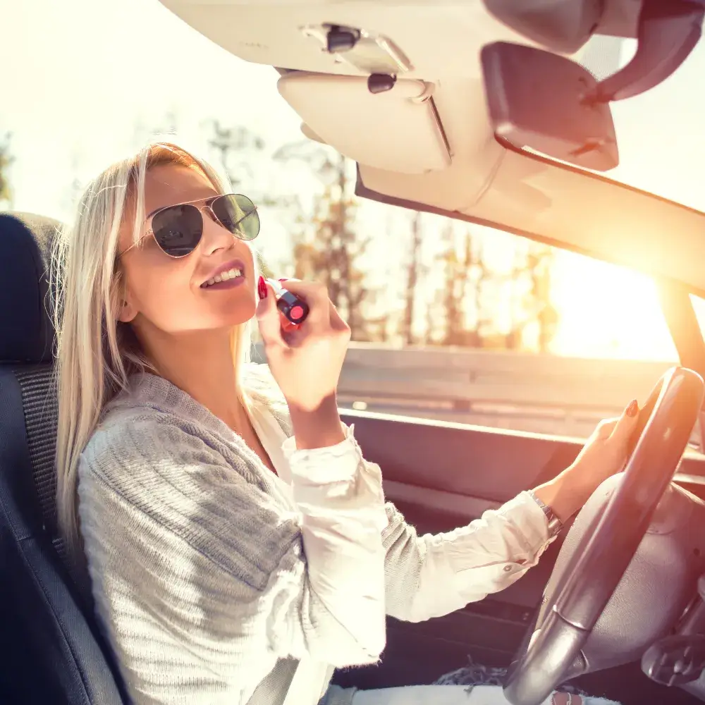 woman applying lipstick inside the car