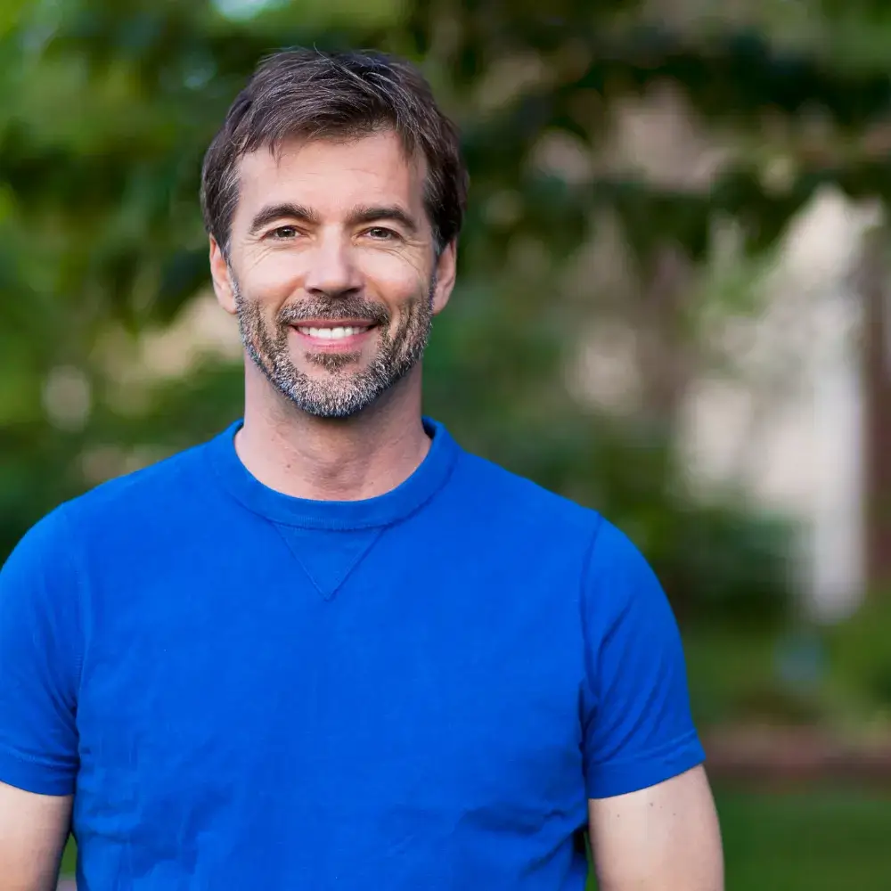 portrait of a man smiling in blue shirt outdoors
