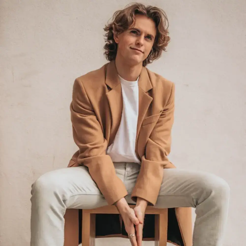 young man in a brown jacket sitting on a chair