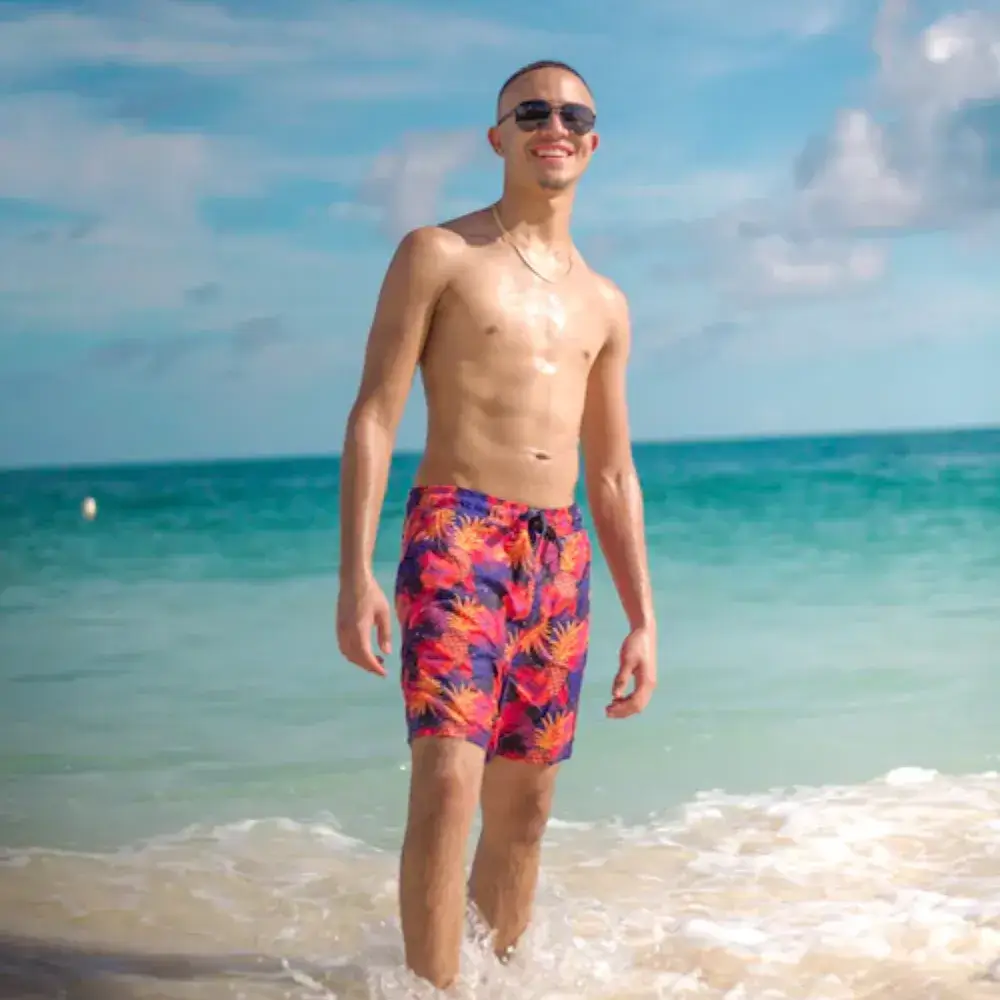 young man wearing floral beach shorts and sunglasses on the beach