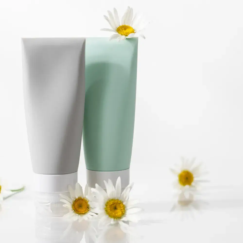 Two tubes of face washes with white flowers against a clean white background