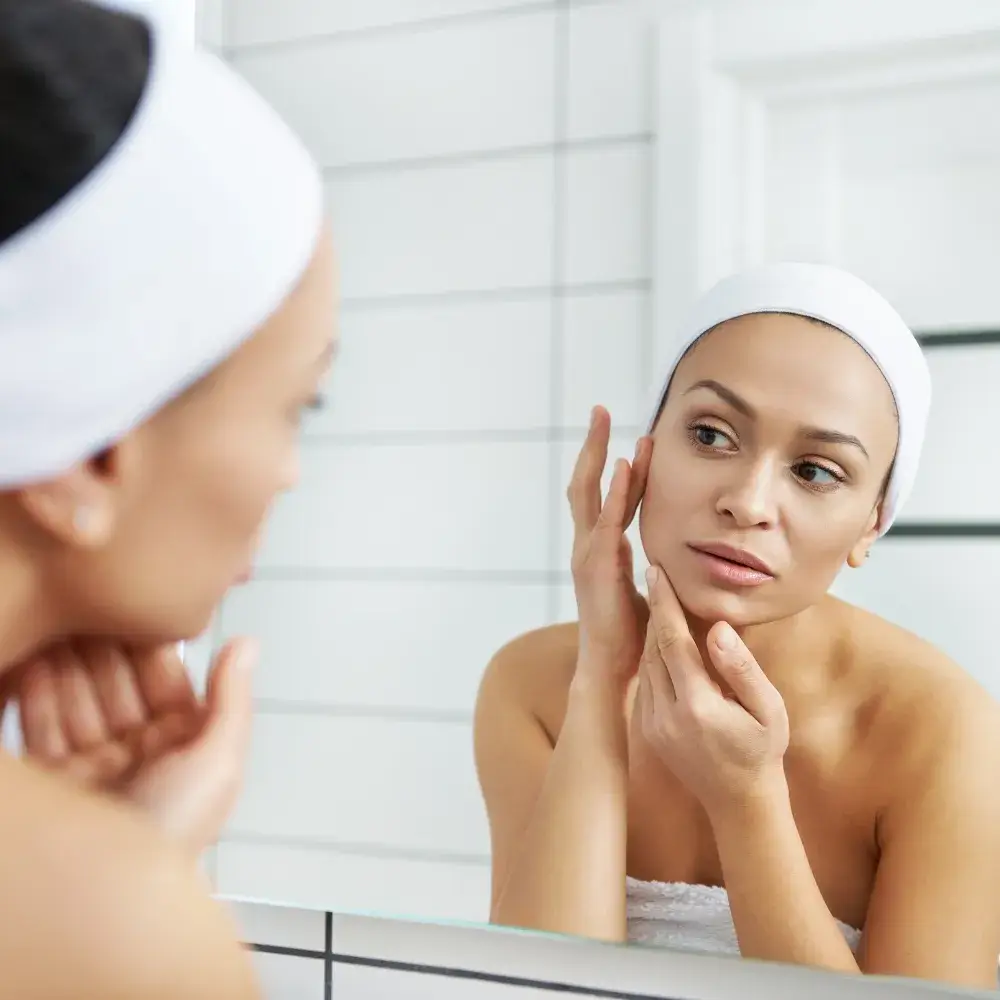 young woman checking her face in front of the mirror