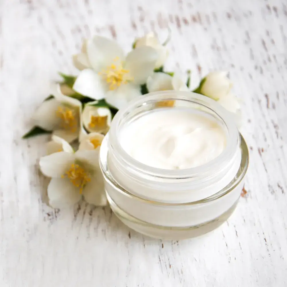 moisturizer in a glass container with white flowers