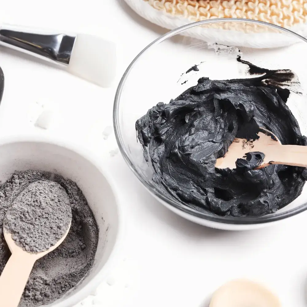 Glass bowls with homemade mud clay mask powder and paste on a clean white background