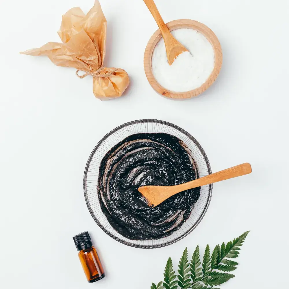 Top view of mud clay mask, sea salt body scrub, and aroma oil on a white background