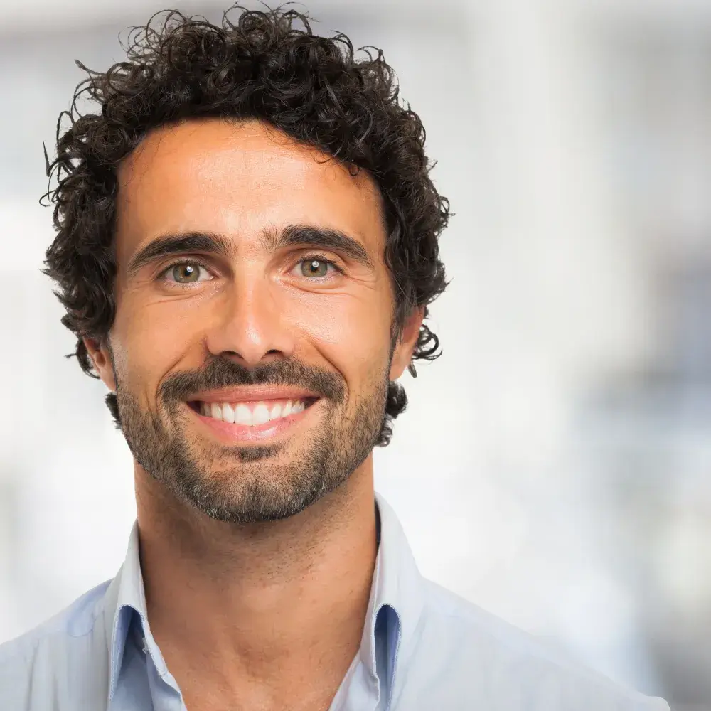 Portrait of a smiling man with curly hair and healthy, clear skin