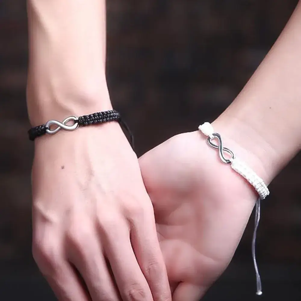 close up of man and woman's hands holding hands with leather bracelets