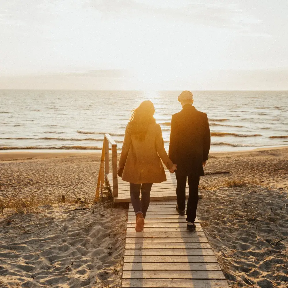 couple holding hands while walking on the beach