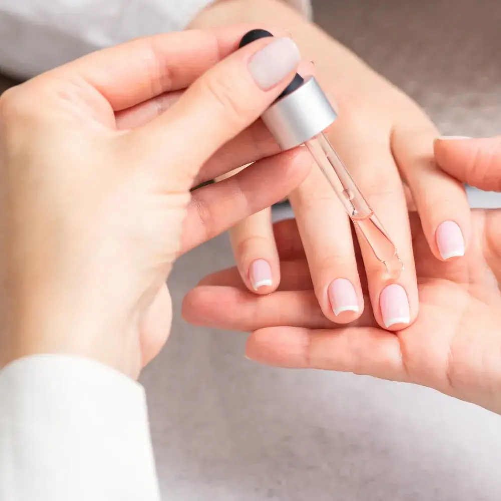 professional manicurist applying nail oil on the french manicured nails