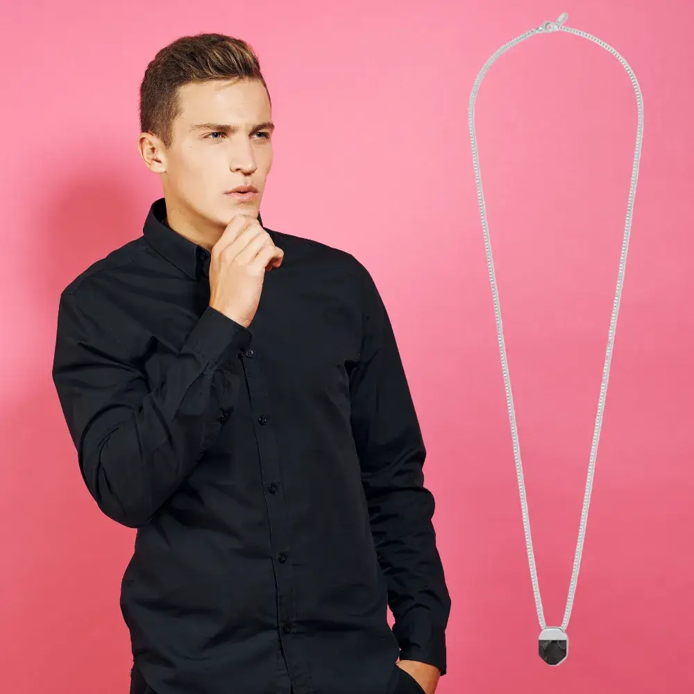 young man posing against a pink background with a silver octo necklace