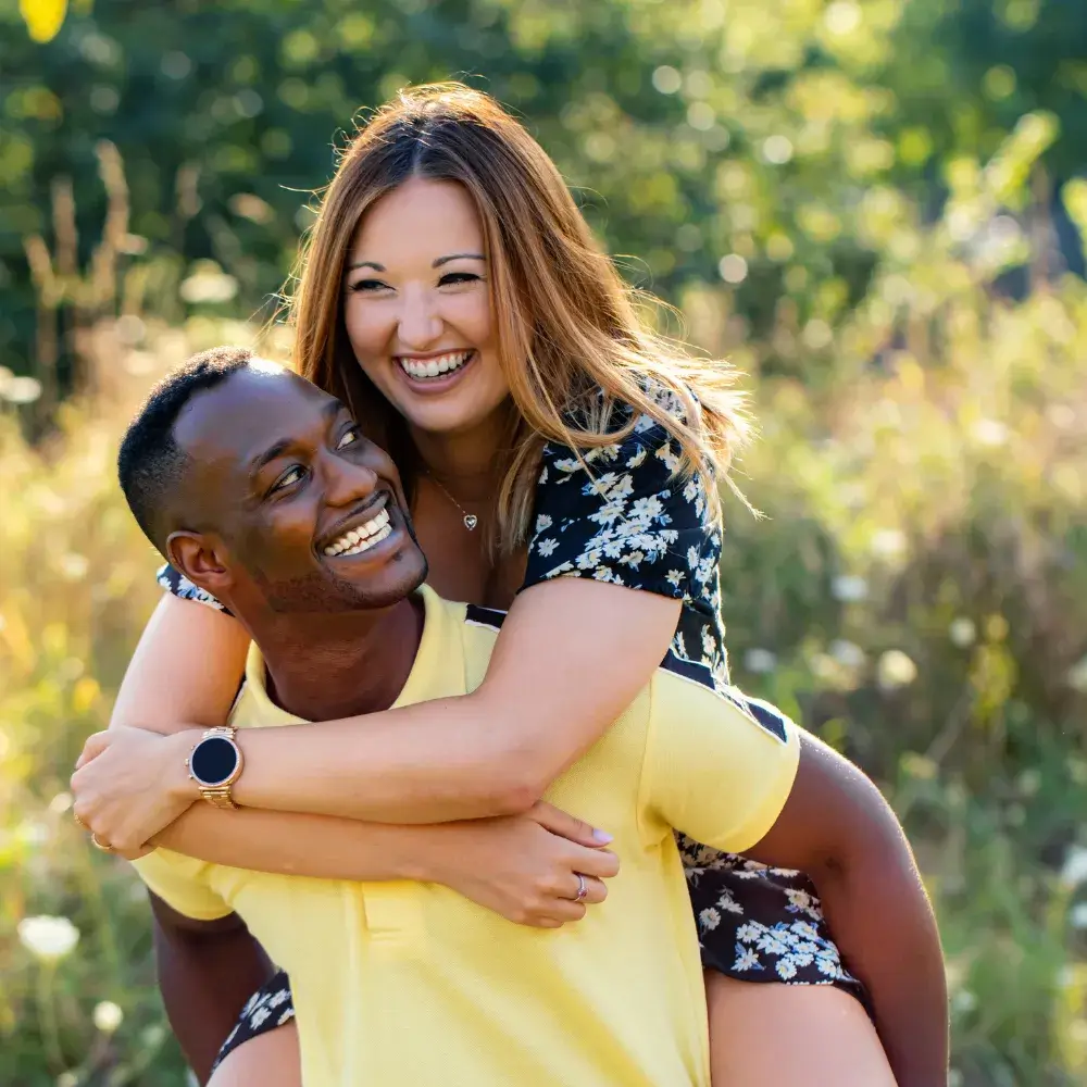happy interracial couple piggybacking outdoors