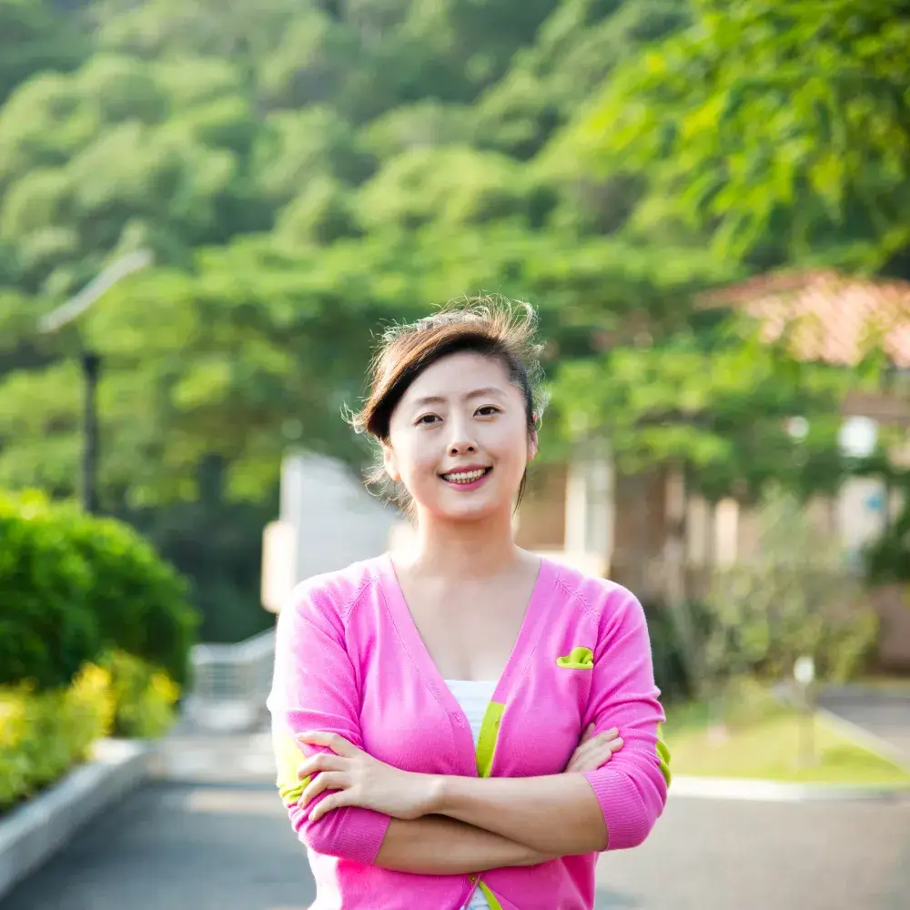 smiling Asian woman wearing a pink sweater outdoors