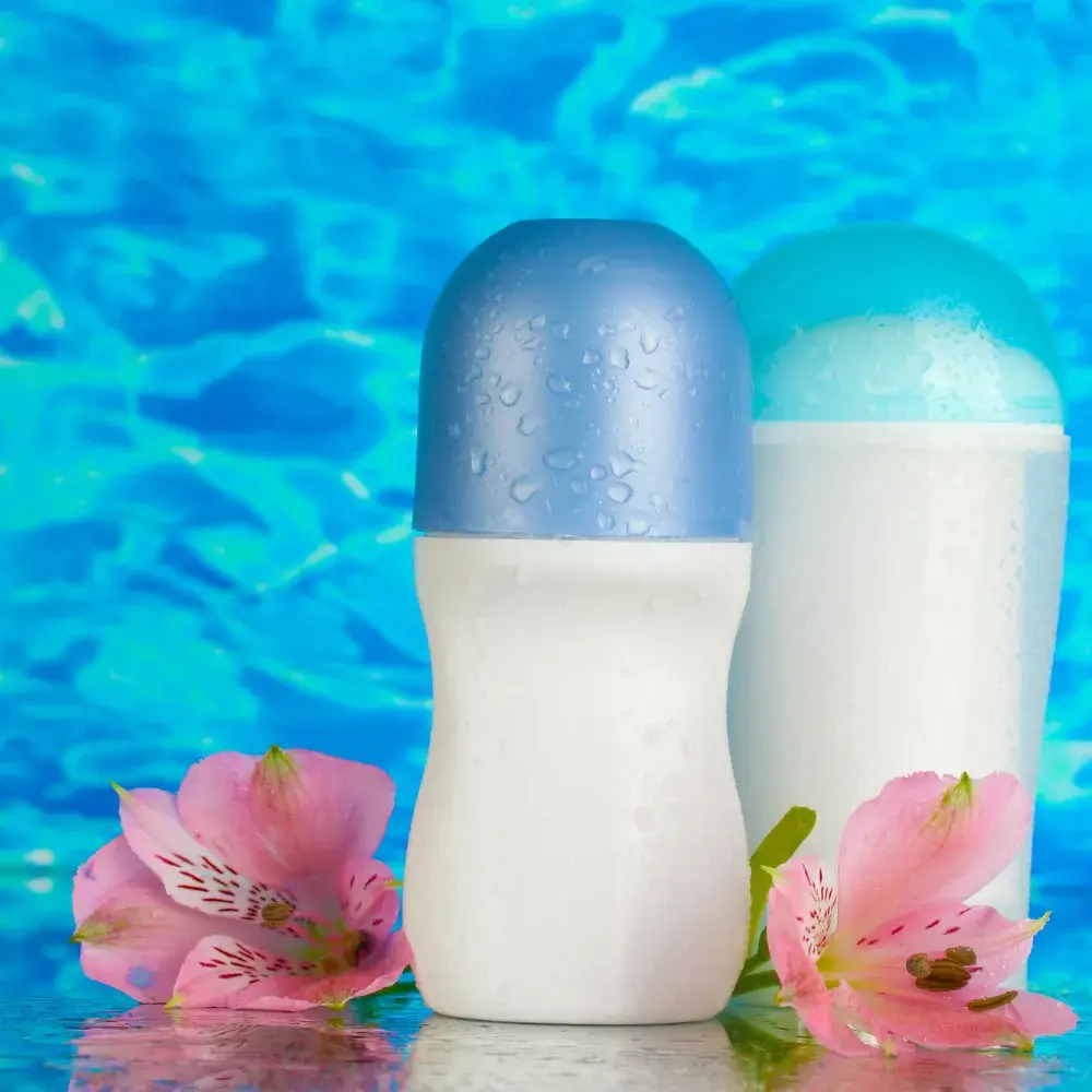 two deodorants with pink flowers and water in the background