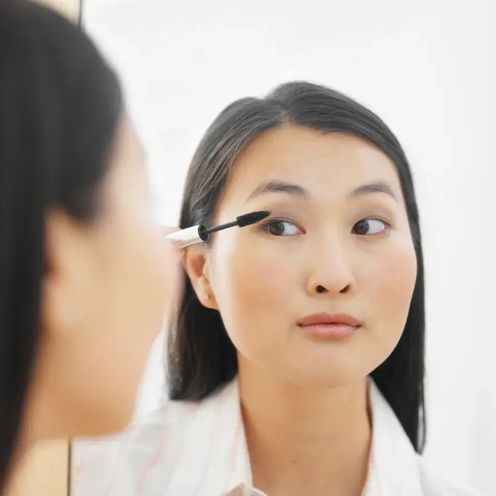 young Asian woman applying mascara