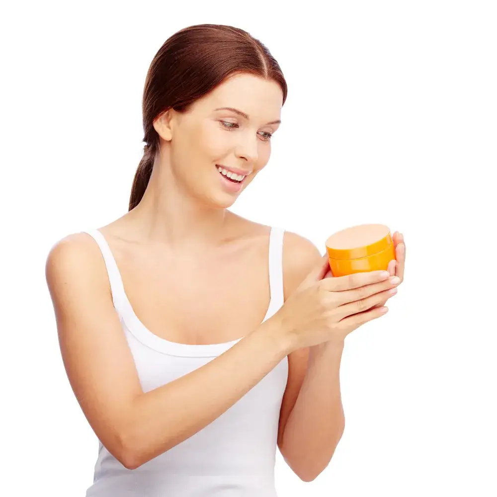 woman in white tank top holding an orange jar of hand cream