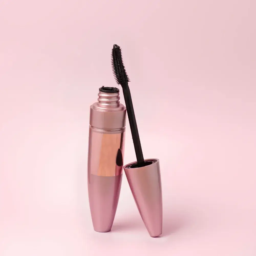 A black mascara in a pink tube is against a pink background