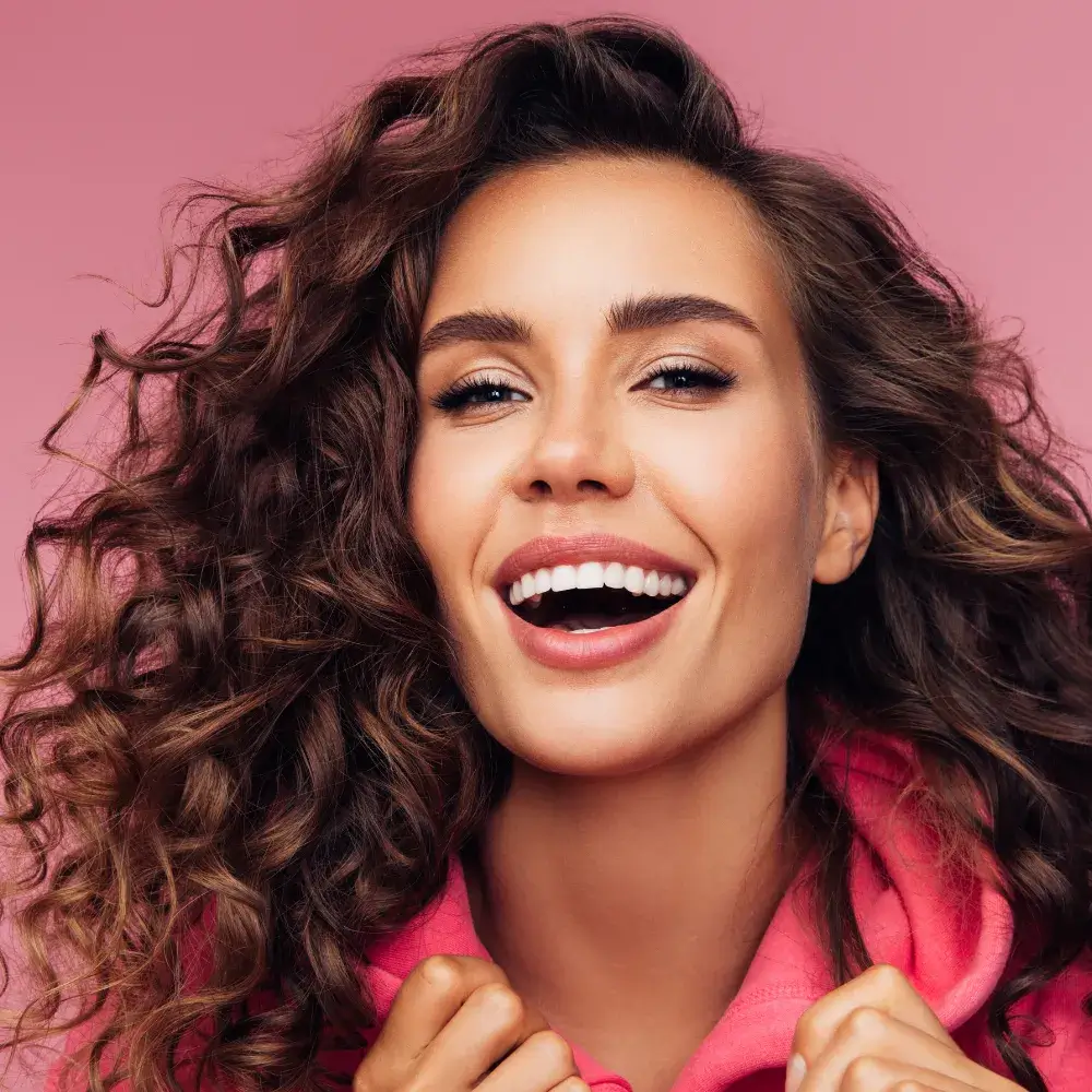 close up portrait of a curly woman in pink smiling