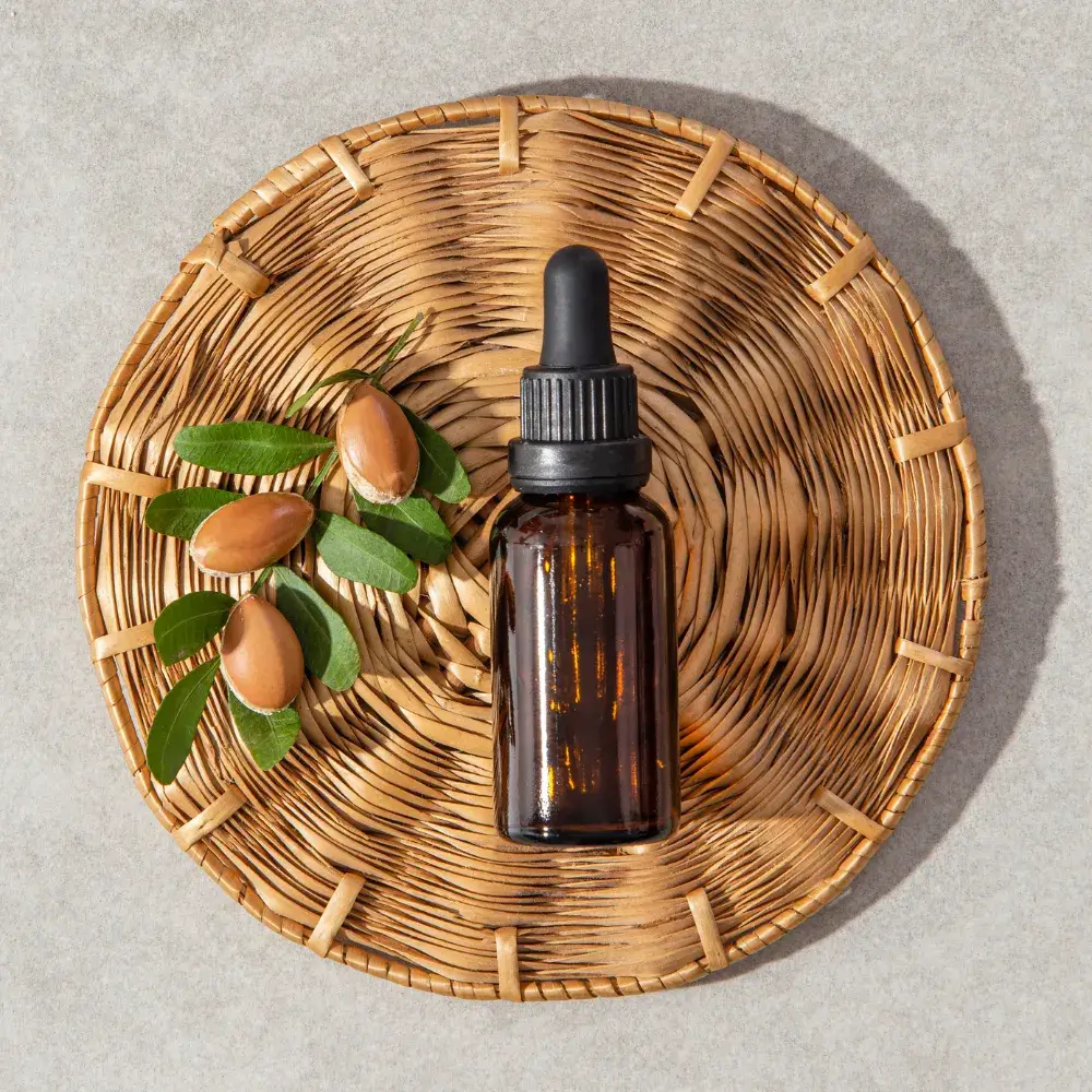 argan seeds and argan oil in a dropper bottle on a wooden tray
