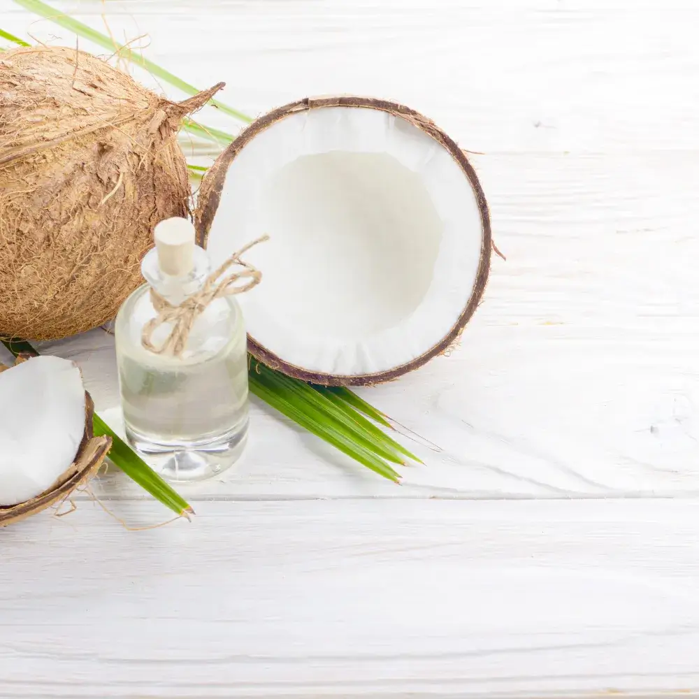 coconut oil in a small glass container with coconut and coconut leaves